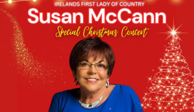 Susan Mc Cann country singer in blue top with a red background and christmas lights